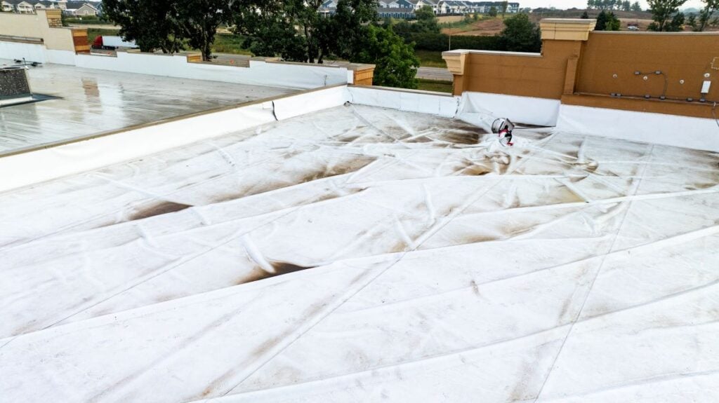 Aerial View Of Commercial Flat Roof With Wrinkled And Stained White Membrane
