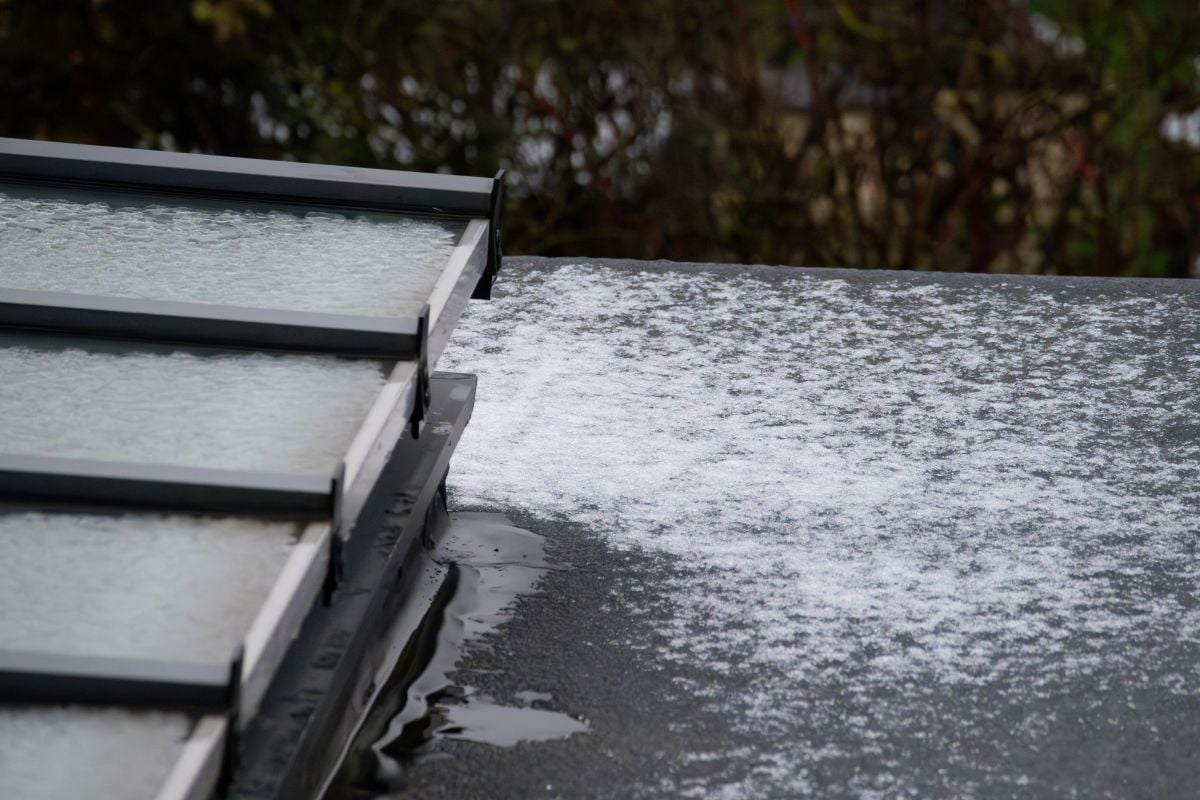 Close Up Of Flat Roof And Glass Skylight Covered In Melting Snow And Ice In Winter