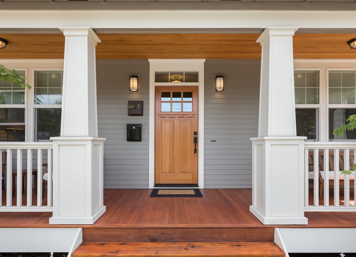Covered porch and front door of beautiful new home with new siding installation
