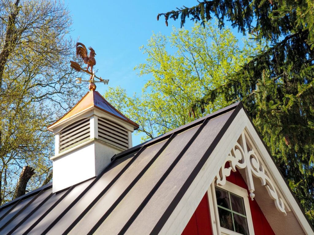 Copper Rooster Weathervane And Cupola On Red Shed Or Barn With Dark Metal Roof