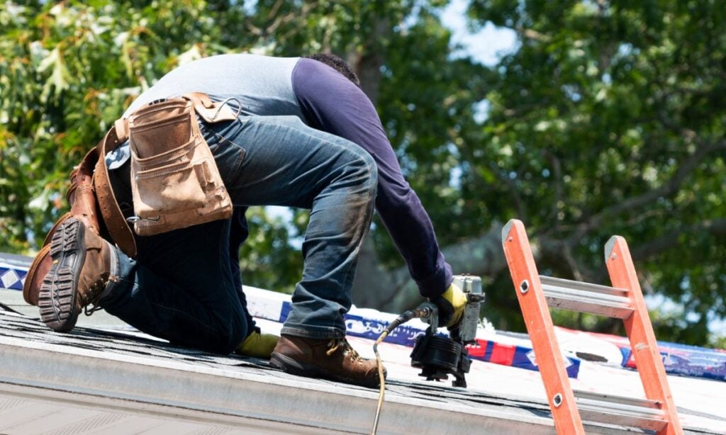 Contractor Using Nail Gun Replacing Roof Shingles On A Roof. How to Choose a Roofing Contractor