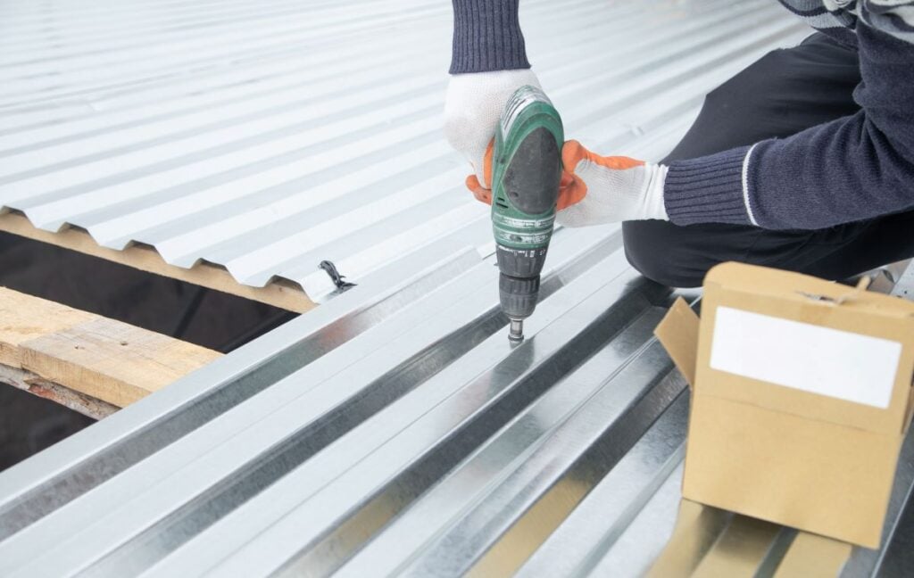 Man Installing Metal Sheet Roof By Electrical Drilling Machine. Metal Roofing Repair